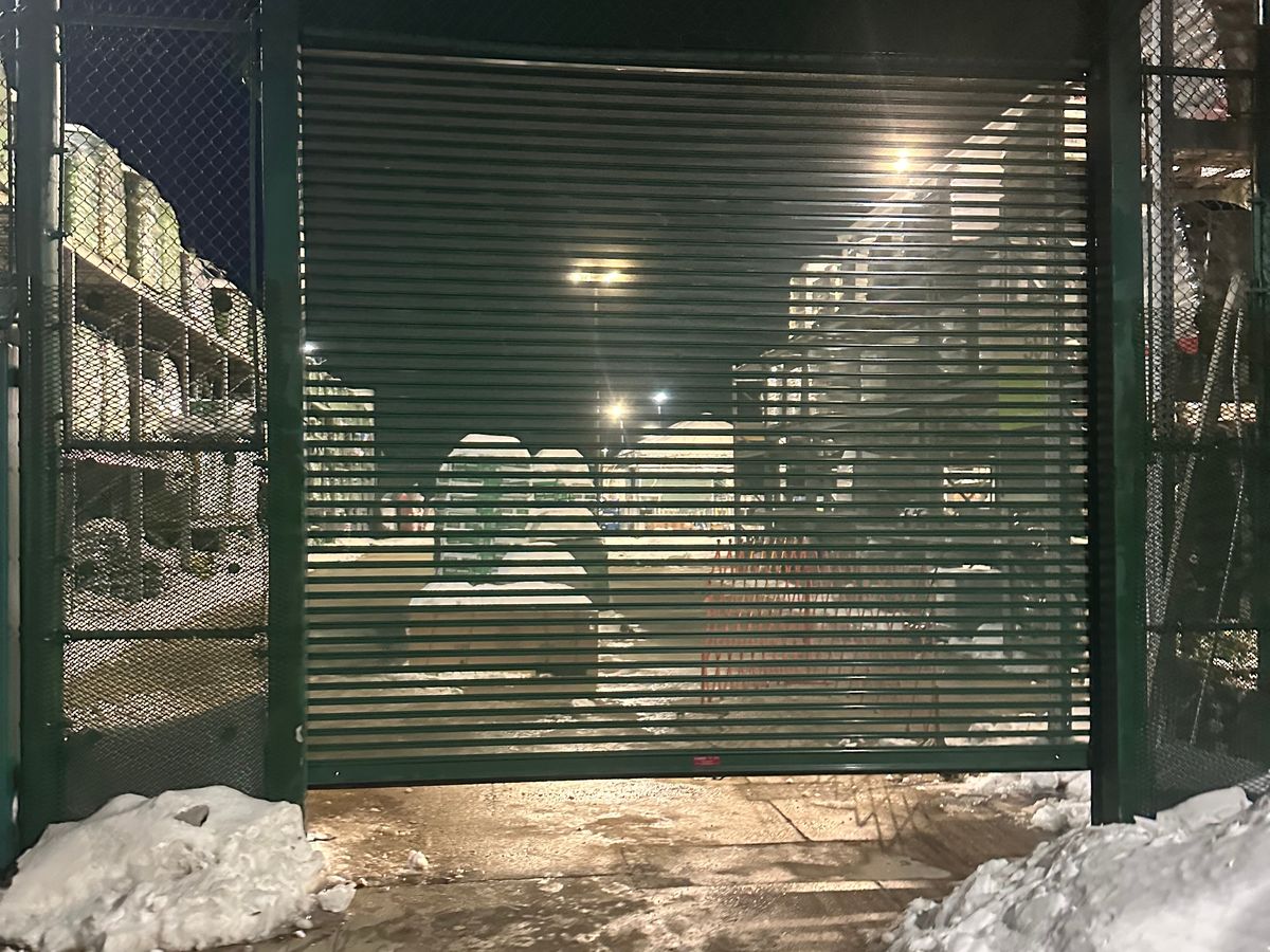 Green commercial security grille door at night in deep snow