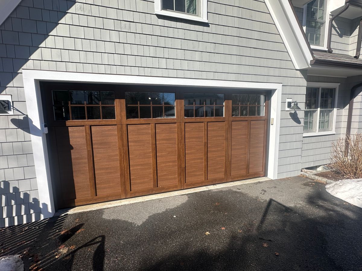 Close-up of custom wood garage door with transom windows on gray colonial home